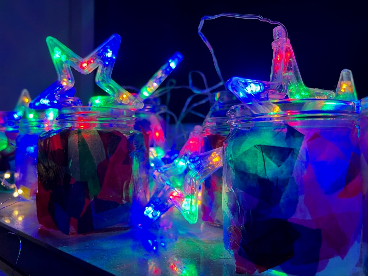  Neon leuchtenden Plastikstangen und Sterne stecken in Gläsern. 