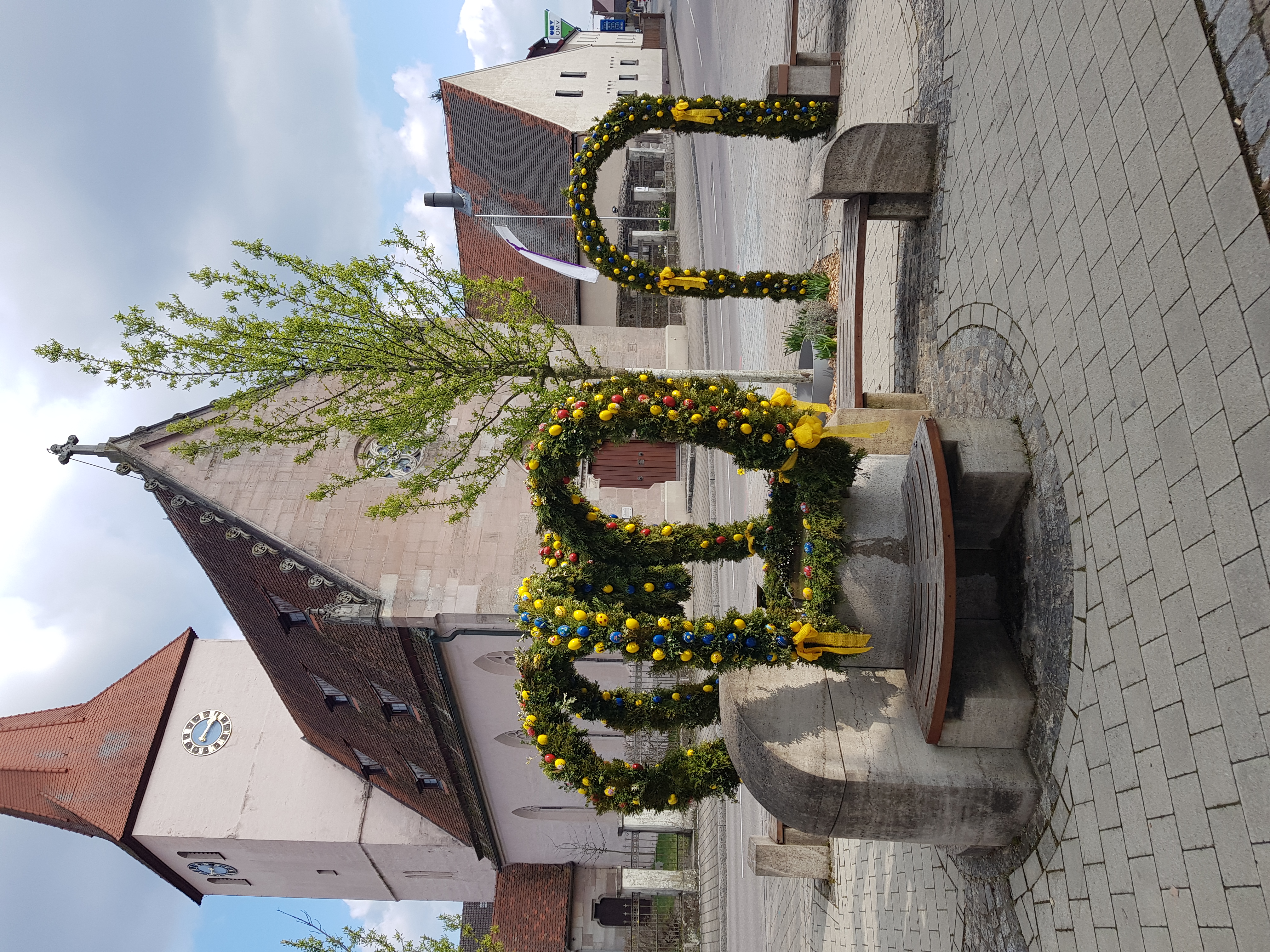  Osterbrunnen in Leerstetten vor dem Hintergrund einer Kirche. 