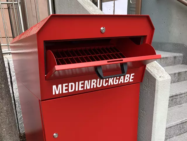Eine rote Mendienrückgabebox mit offener Einworf-Klappe.
