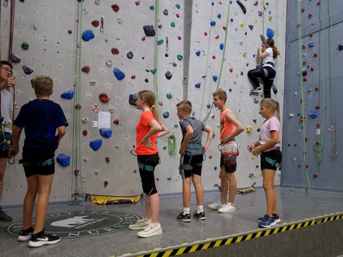 Kinder stehen in einer Reihe vor einer Boulder-Wand